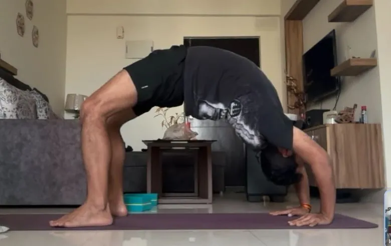 Yogesh in a deeper backbend on a purple mat, seen from the side